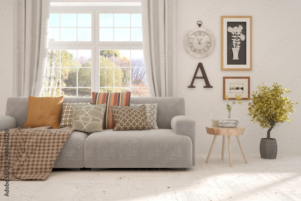 Stylish room in white color with sofa and autumn landscape in window. Scandinavian interior design. 