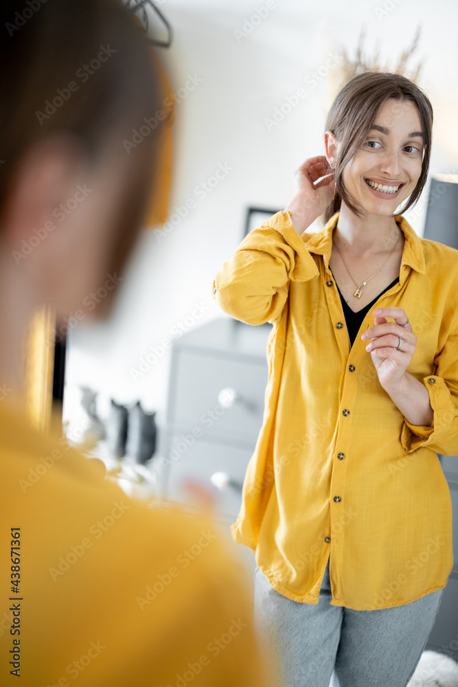 年轻开朗的女人照镜子做发型，准备在走廊出门