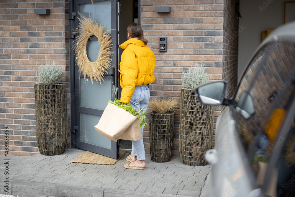 Woman comes home with bags full of fresh groceries, Opening the entrance door of her house. Concept 