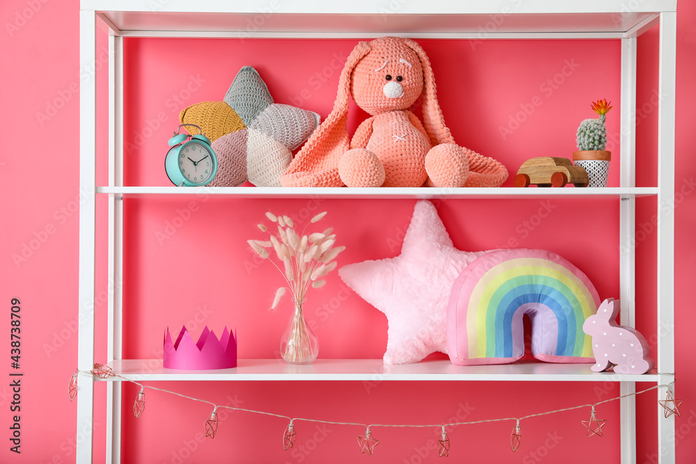 Shelf with toys and decor near color wall