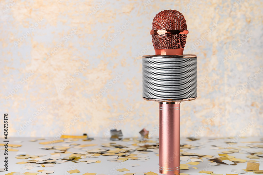 Modern microphone and confetti on light background