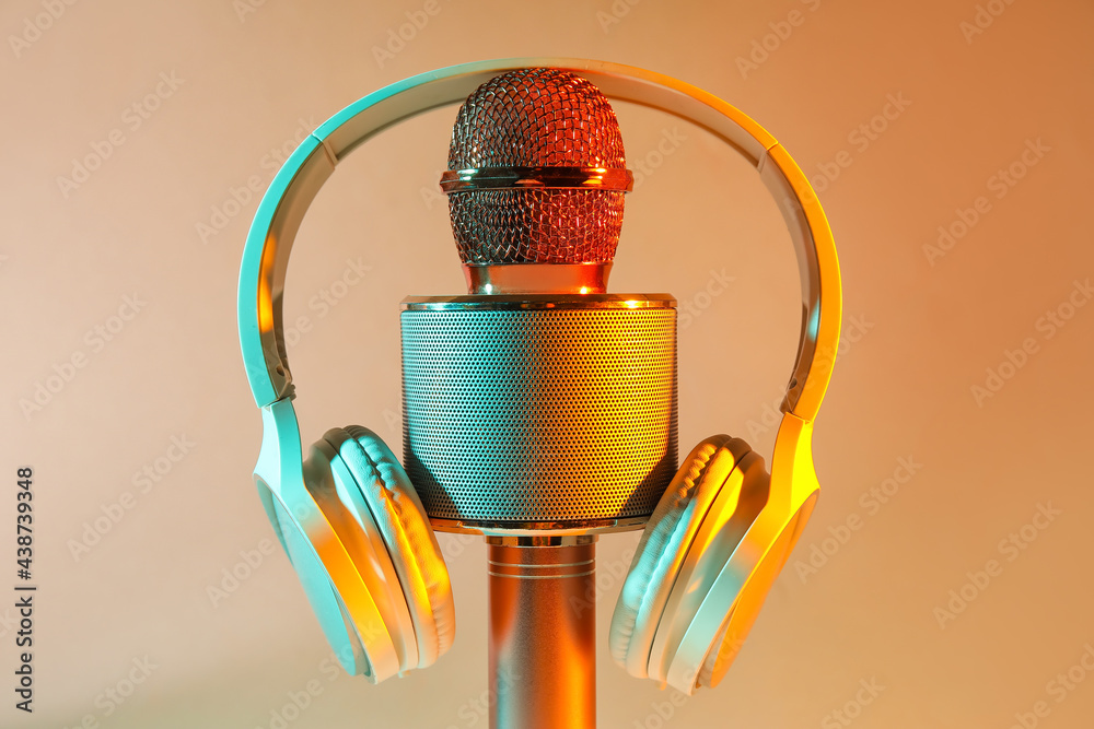 Modern microphone with headphones on color background, closeup