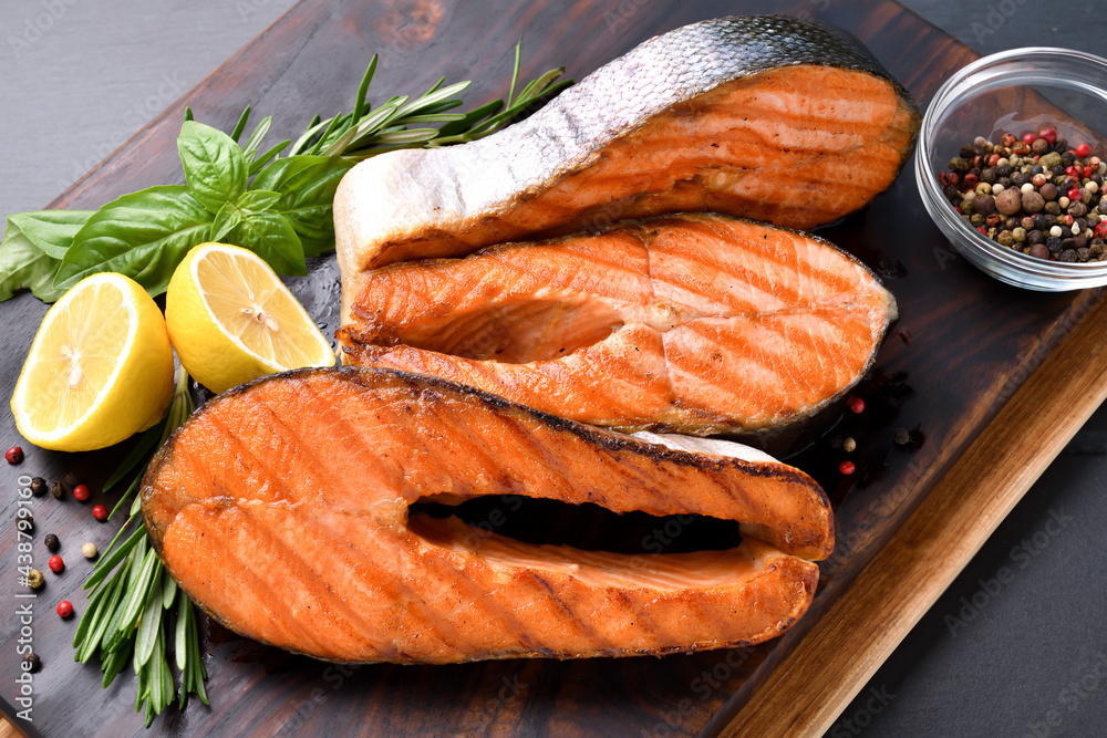 Grilled salmon steaks with ingredients on wooden cutting board in the kitchen