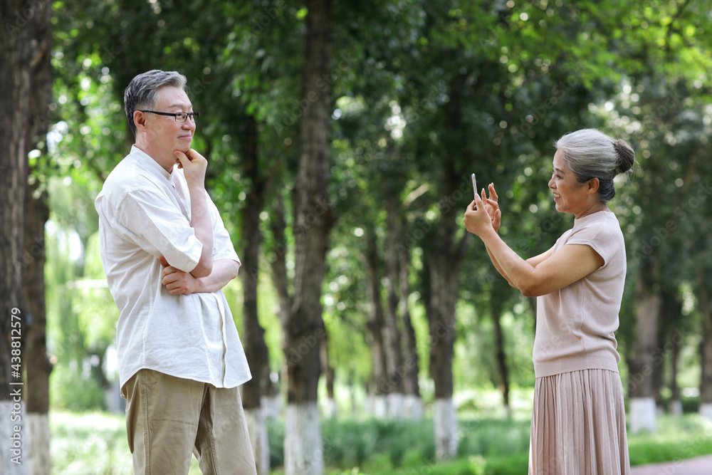 幸福的老夫妇在公园里用手机拍照