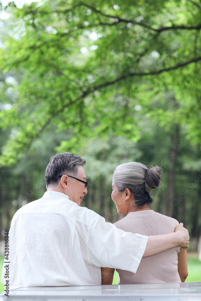 快乐的老夫妇坐在户外公园的椅子上