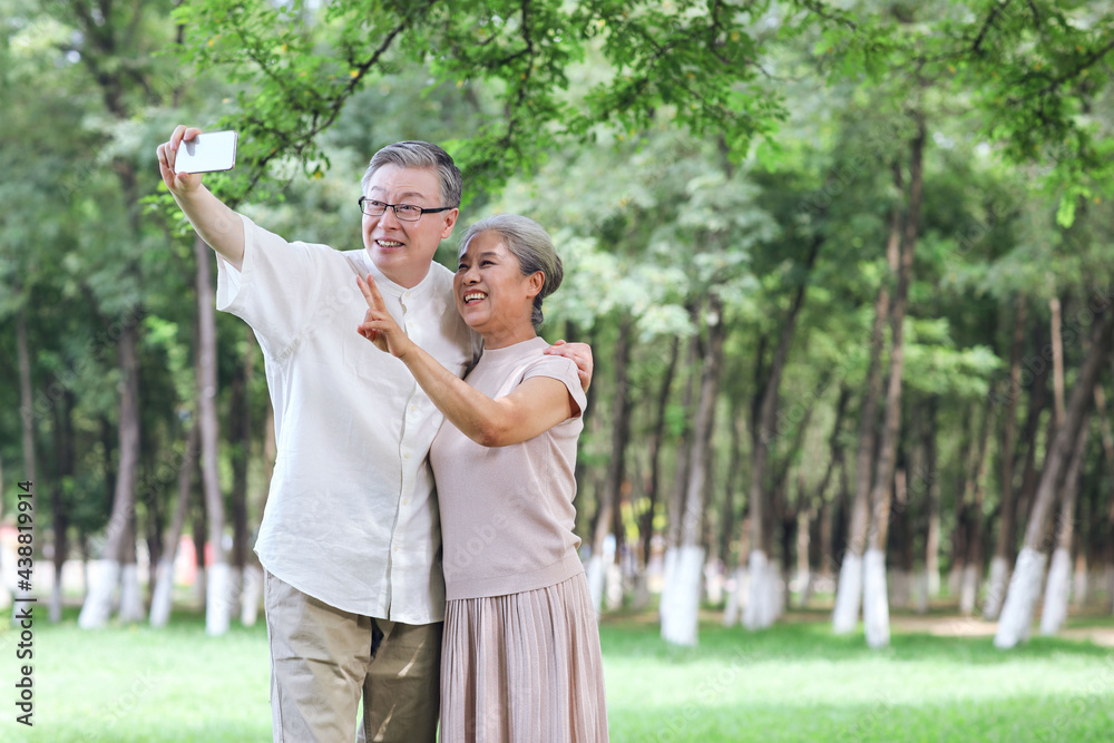 幸福的老夫妻在公园用手机自拍