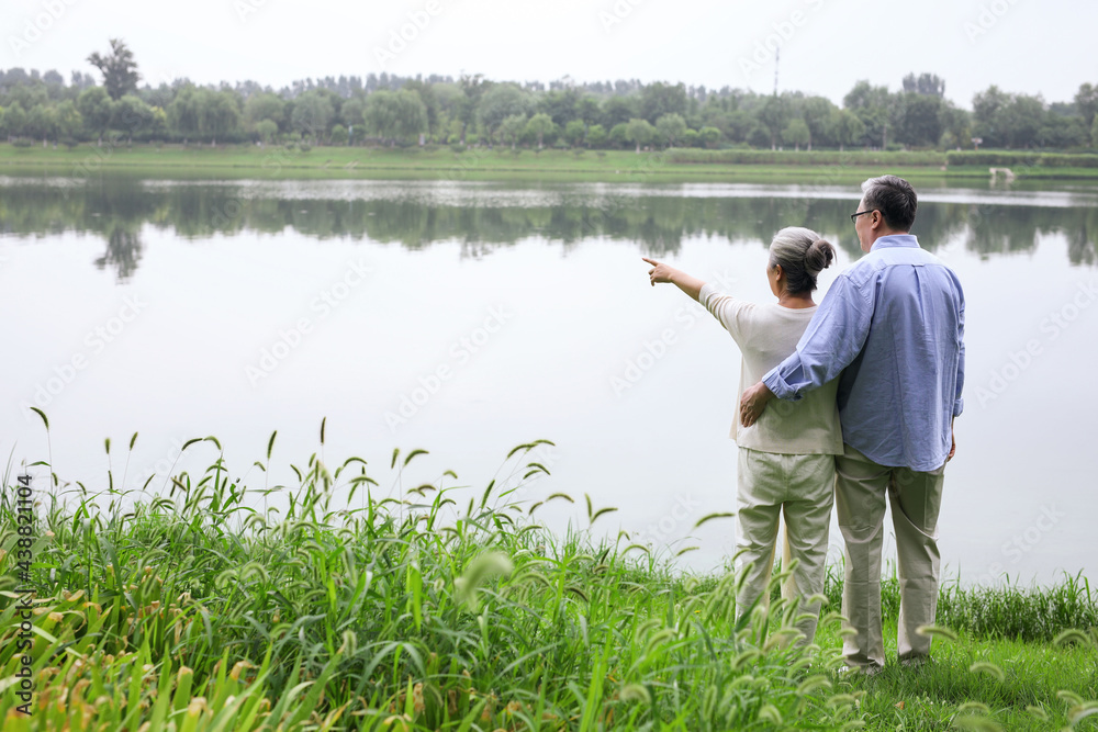 Happy old couple watching the scenery by the lake