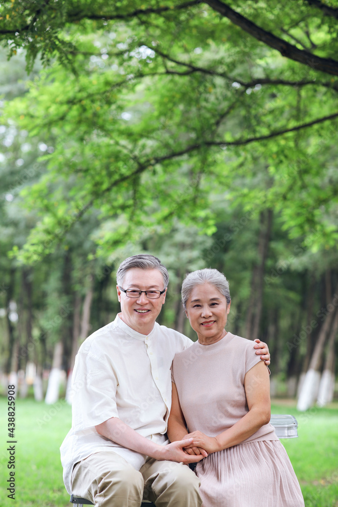 Happy old couple sitting on chairs in outdoor park