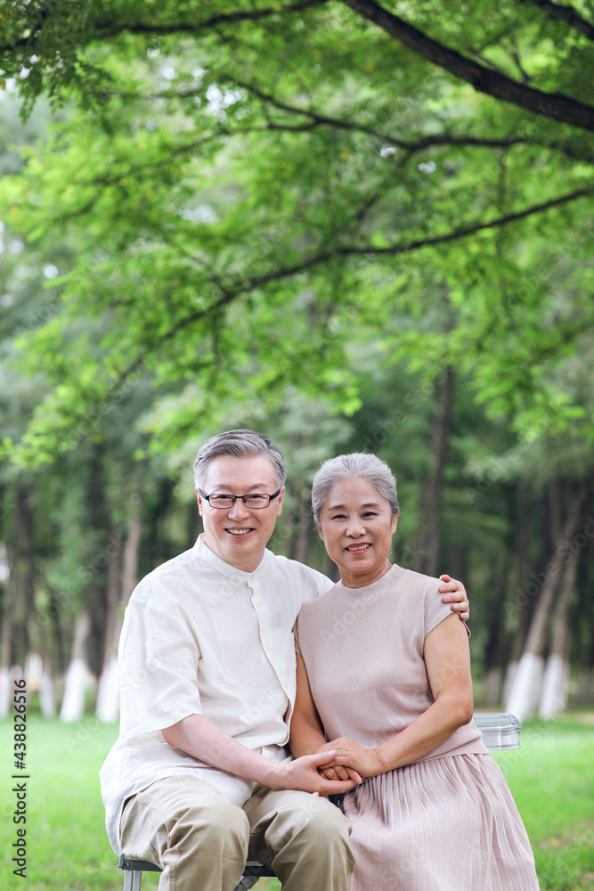 Happy old couple sitting on chairs in outdoor park