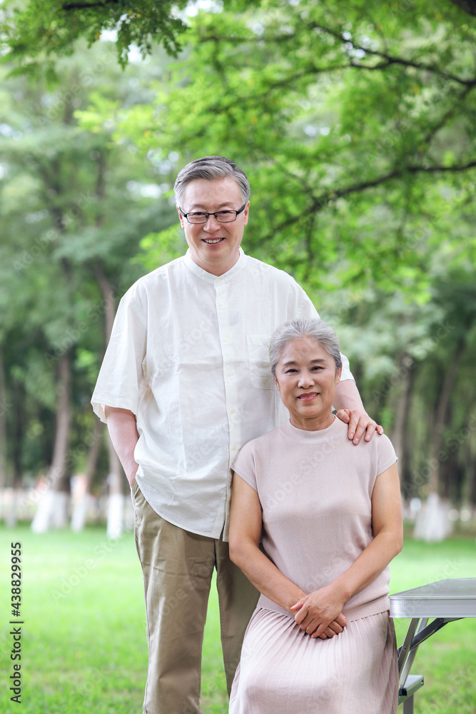 Happy old couple sitting on chairs in outdoor park