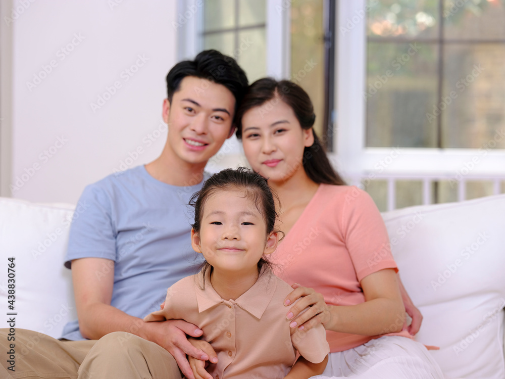 A happy family of three is sitting on the sofa in the living room