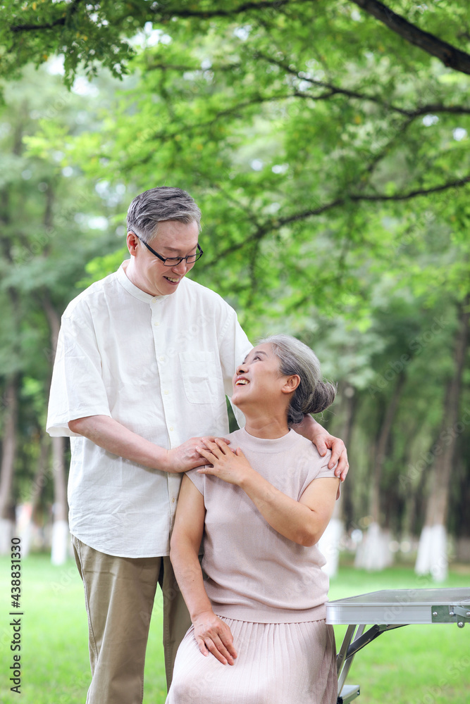 快乐的老夫妇坐在户外公园的椅子上