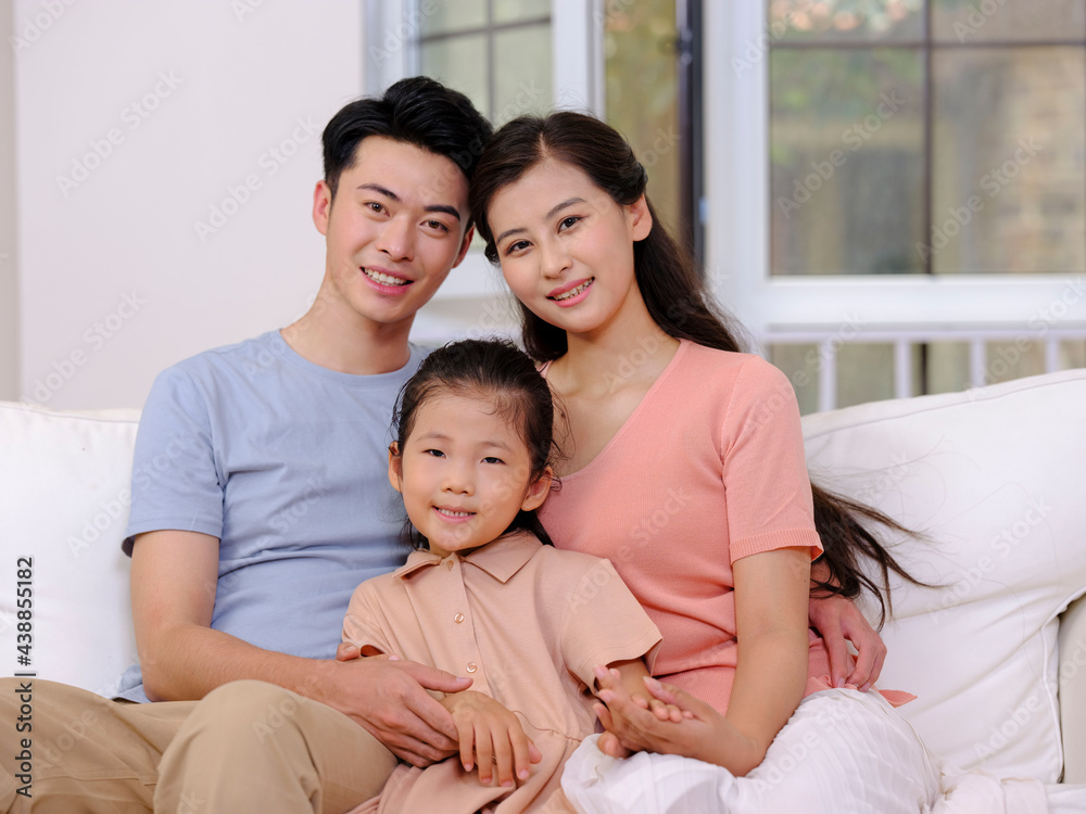 A happy family of three is sitting on the sofa in the living room