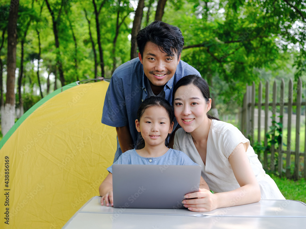 Happy family of three use computer to surf the Internet outdoors