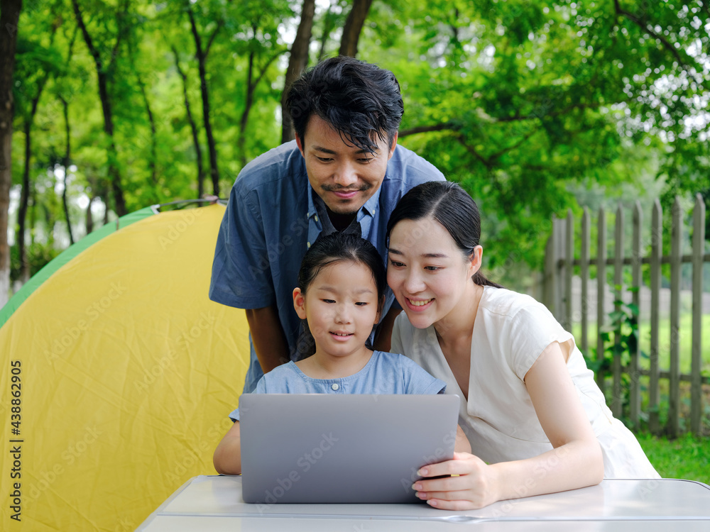 Happy family of three use computer to surf the Internet outdoors