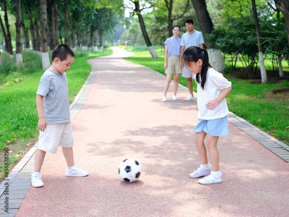 Happy family of four playing football in the park