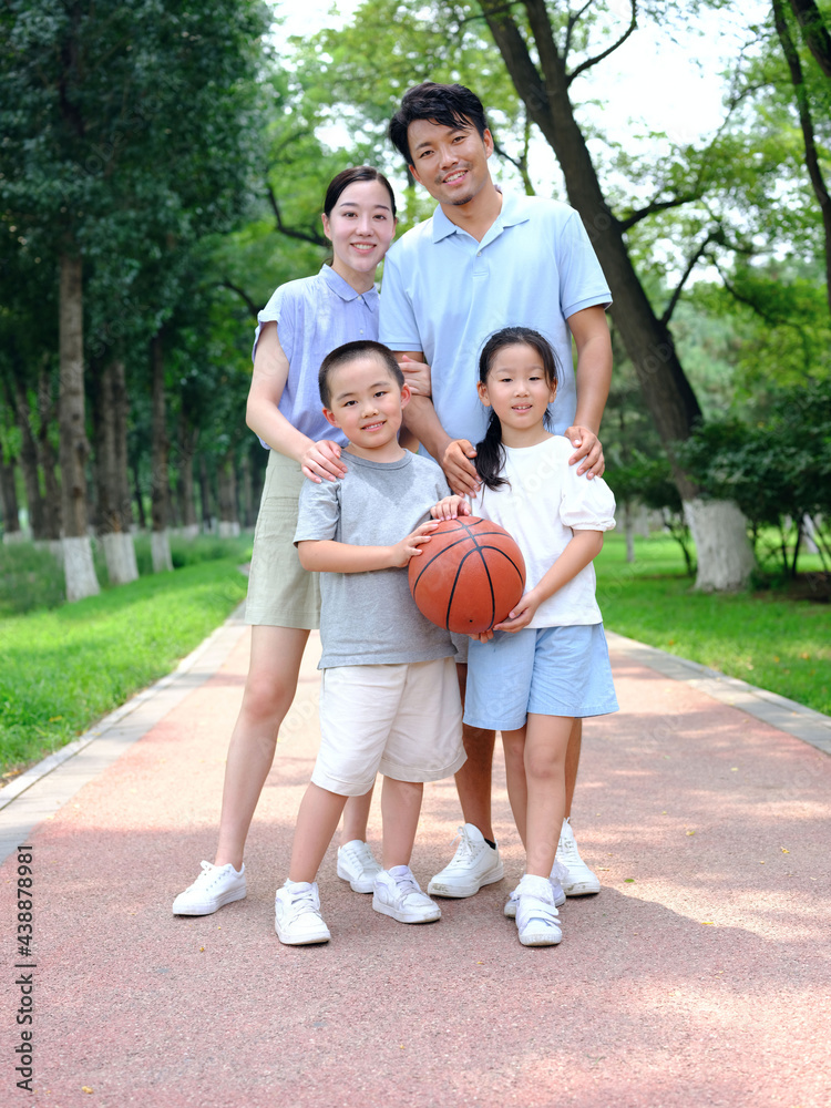 Happy family of four playing in the park