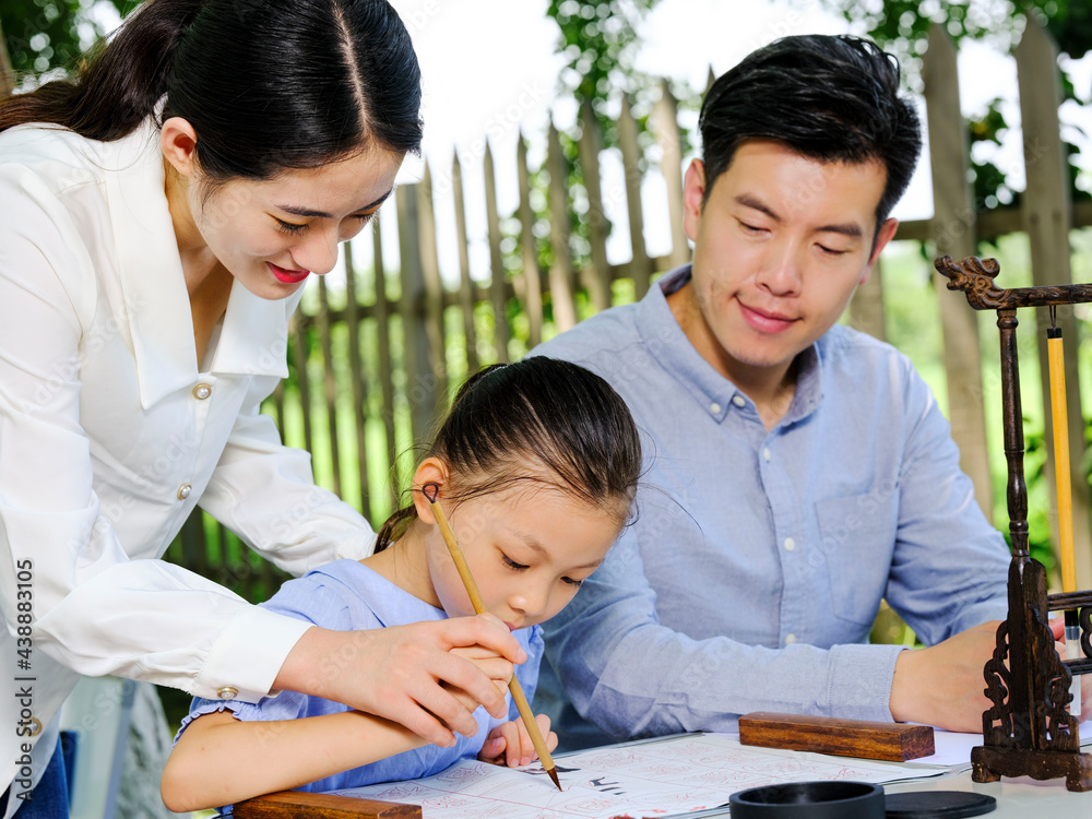 Happy family of three writing calligraphy outdoors