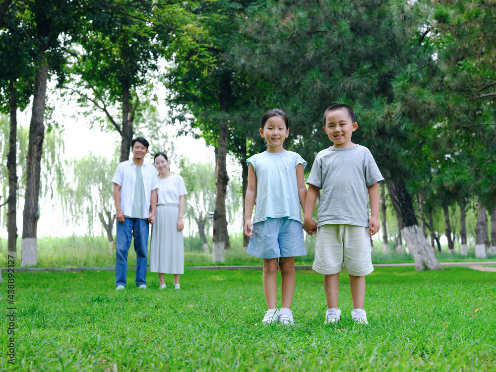 Happy family of four playing in the park