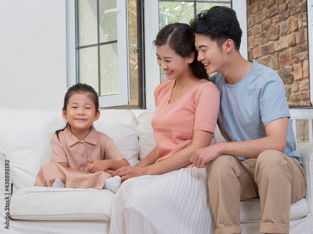 A happy family of three is sitting on the sofa in the living room