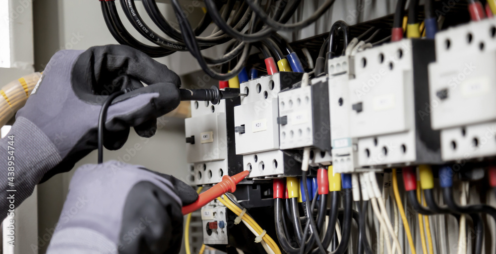 Electrician engineer tests electrical installations and wires on relay protection system. Adjustment