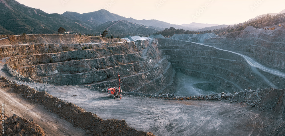 砾石采石场，带露台、成堆的石头和红色破碎机。山脉背景全景