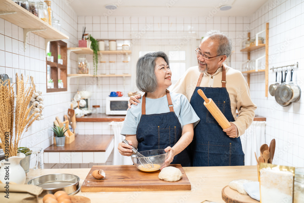 Loving Senior elderly couple stand in kitchen at house enjoy cook food	