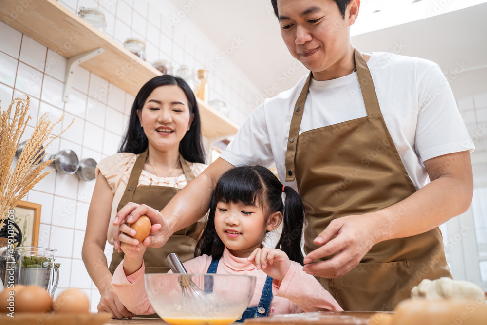 厨房里的幸福家庭父母教孩子吃鸡蛋，在家做饭