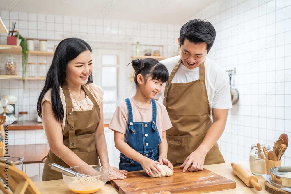 厨房里的幸福家庭父母教孩子在家里烤面包和食物