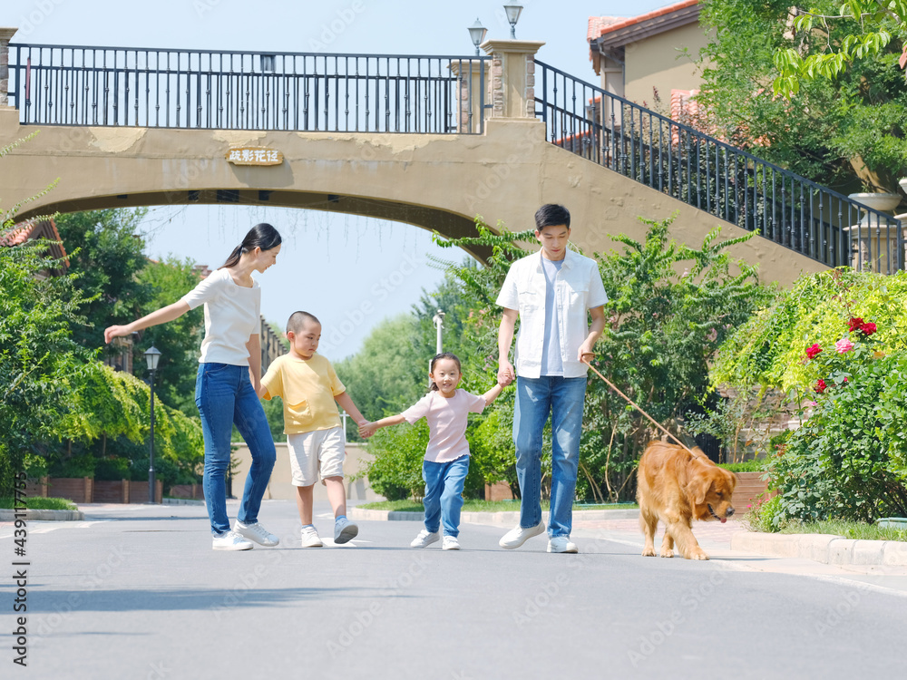 Happy family of four walking dogs outdoors