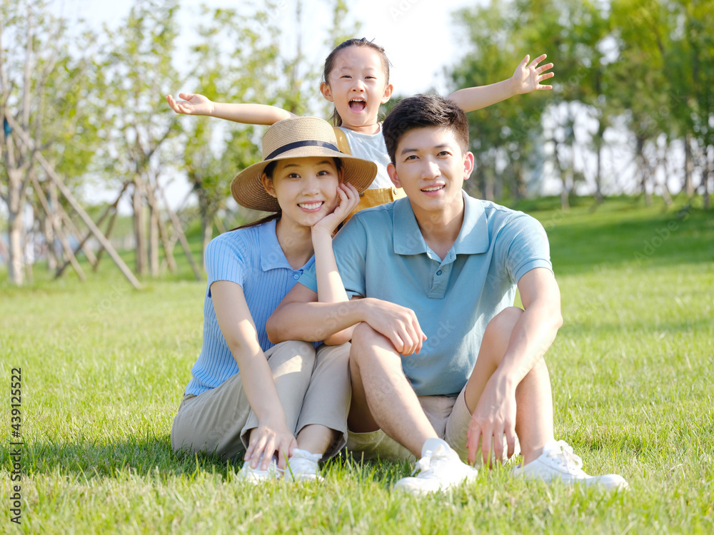 Happy family of three sitting on the grass