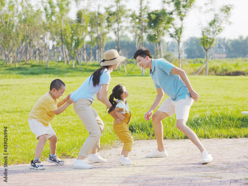 Happy family of four playing games in the park