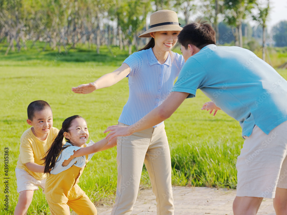 Happy family of four playing games in the park