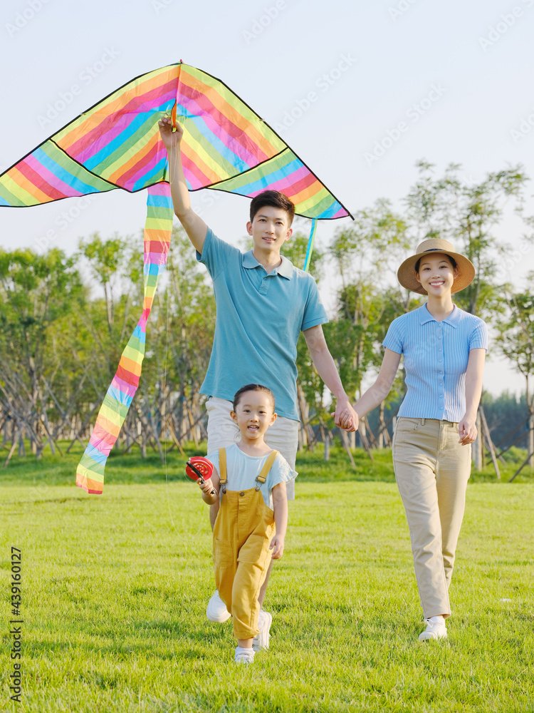 Happy family of three flying kites in the park