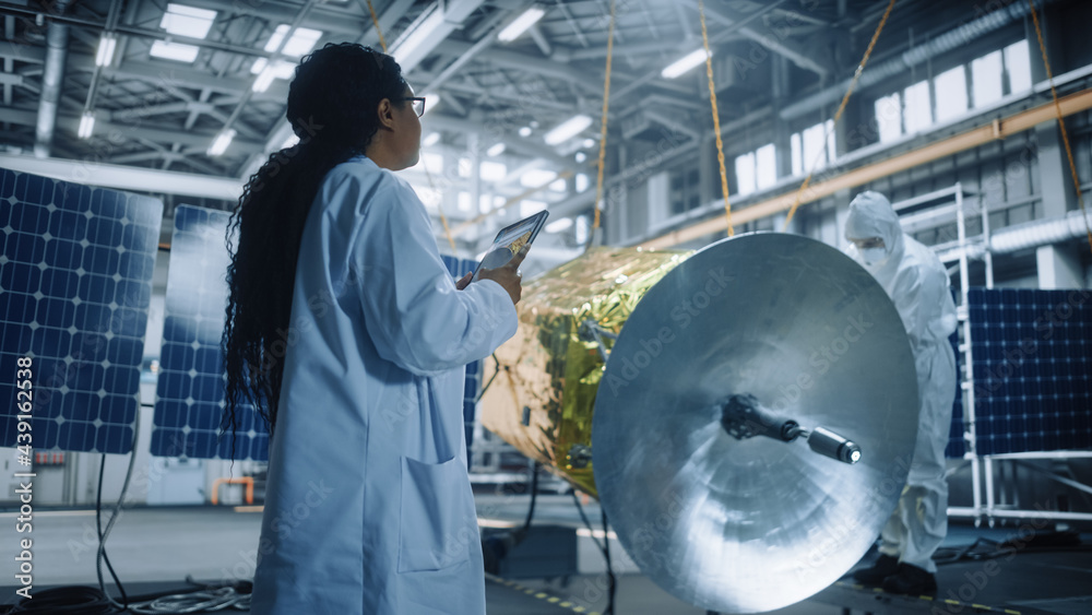 Female Engineer Uses Digital Tablet Computer while Working on Satellite Construction. Aerospace Agen