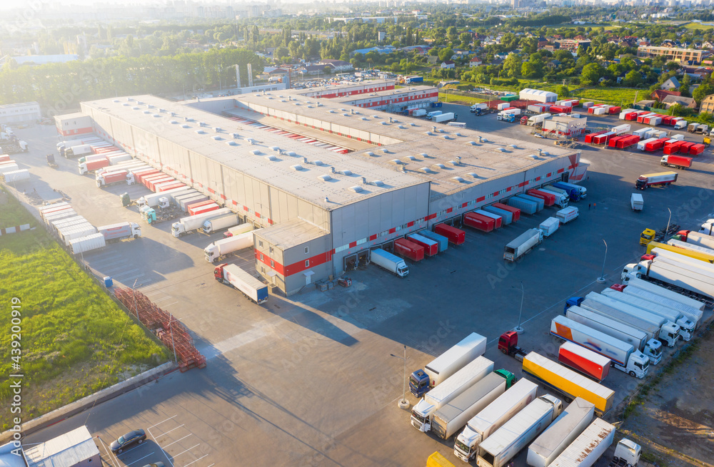 Logistics park with warehouse and outside storage of wooden pallets. Semi-trailers trucks standing o