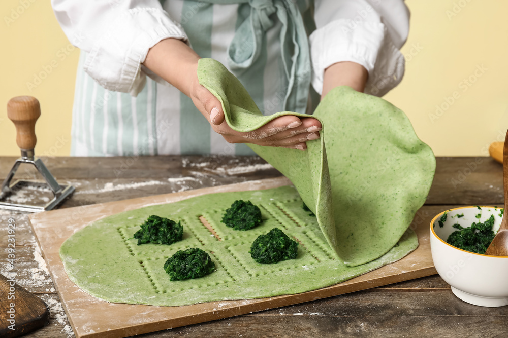 Female chef making delicious ravioli at table, closeup