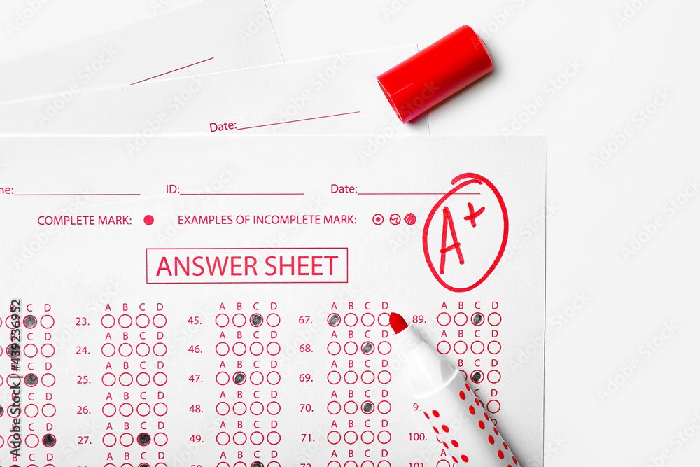 Checked answer sheet and marker on white background, closeup