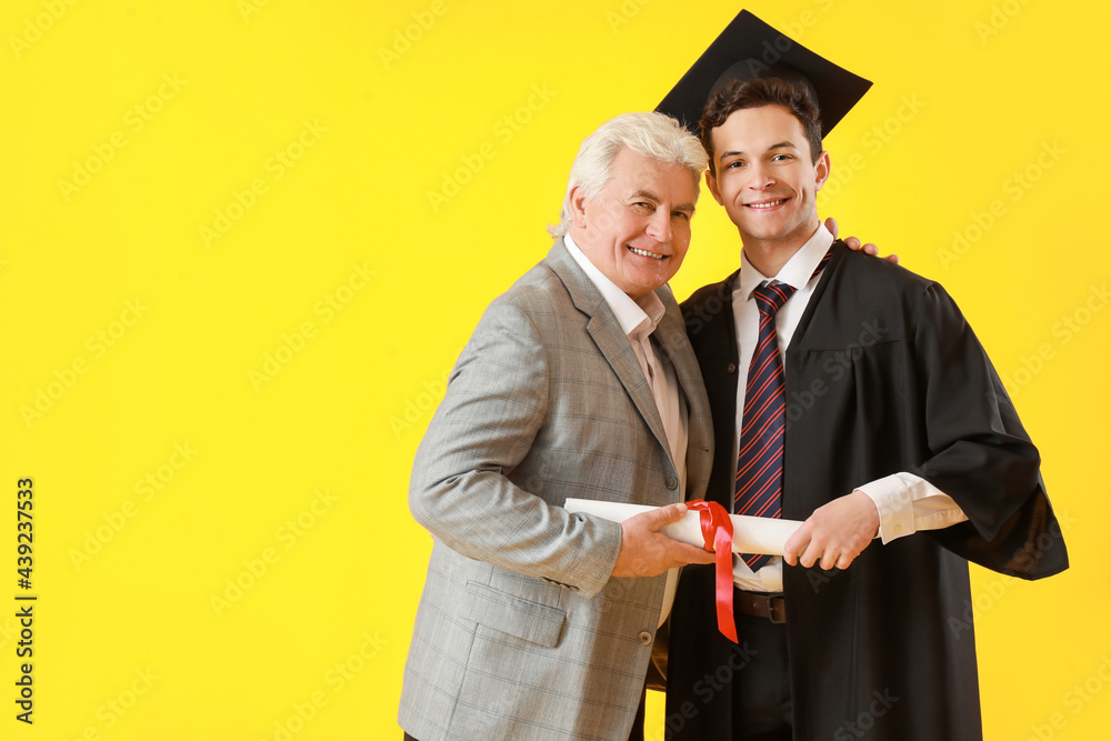 Happy male graduation student with his father on color background