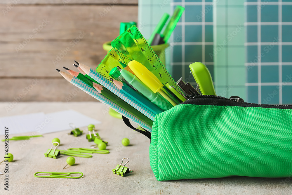 Pencil case with stationery on light background