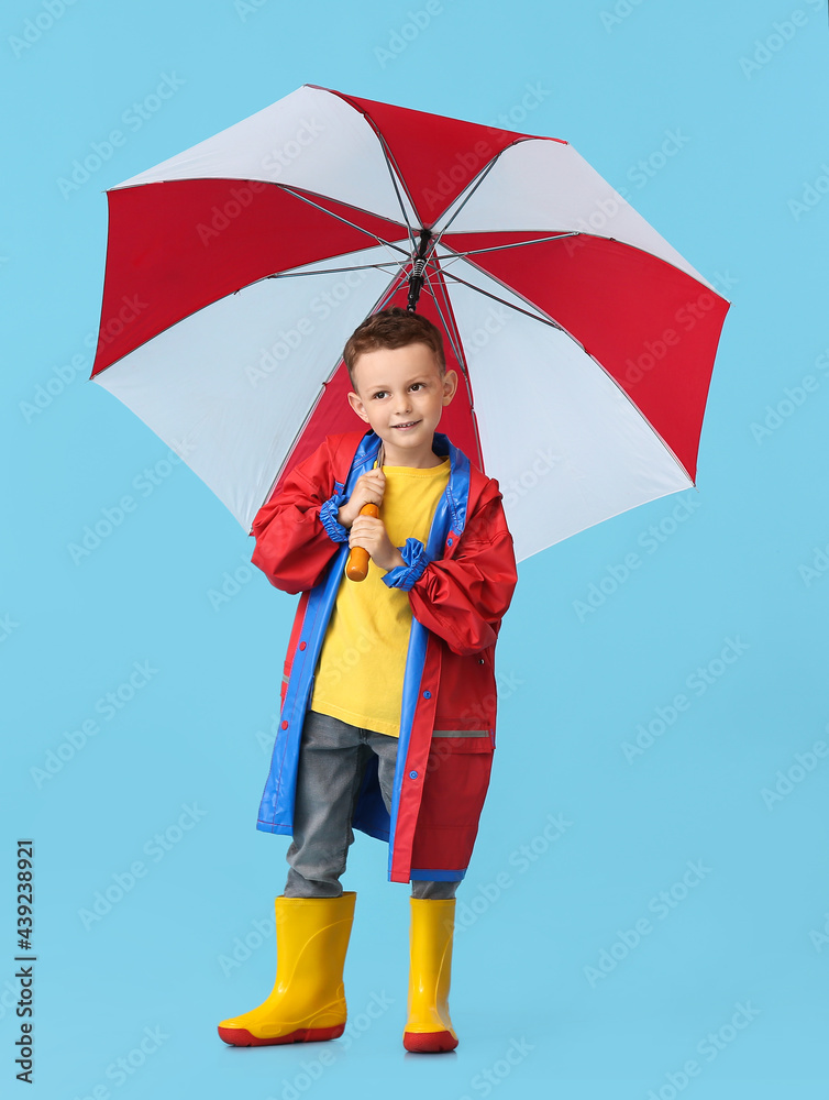 可爱的小男孩穿着雨衣，背景是雨伞