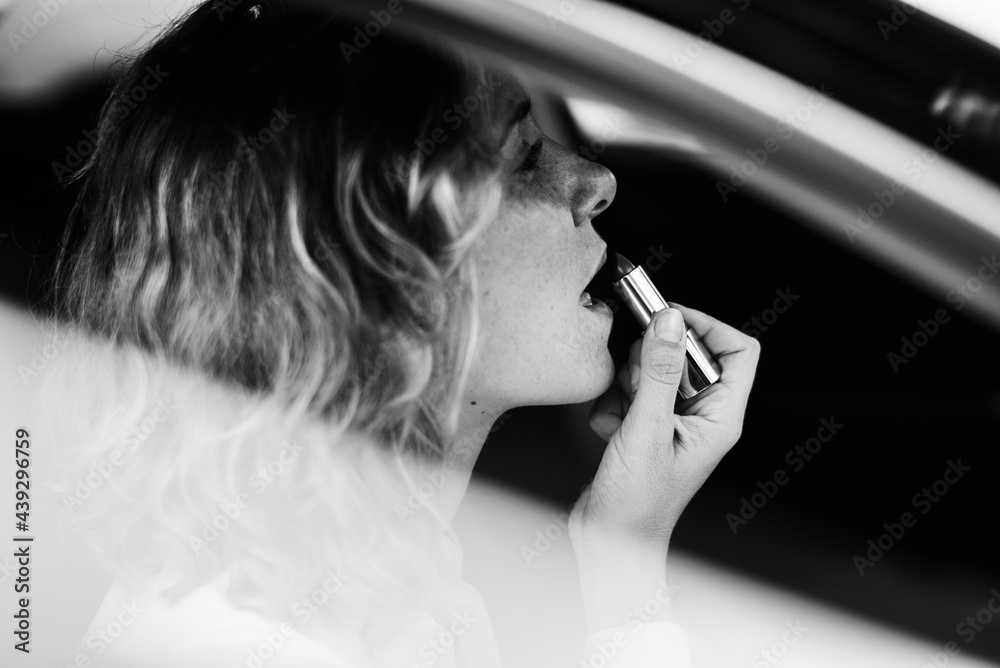 Woman putting on lipstick in a car