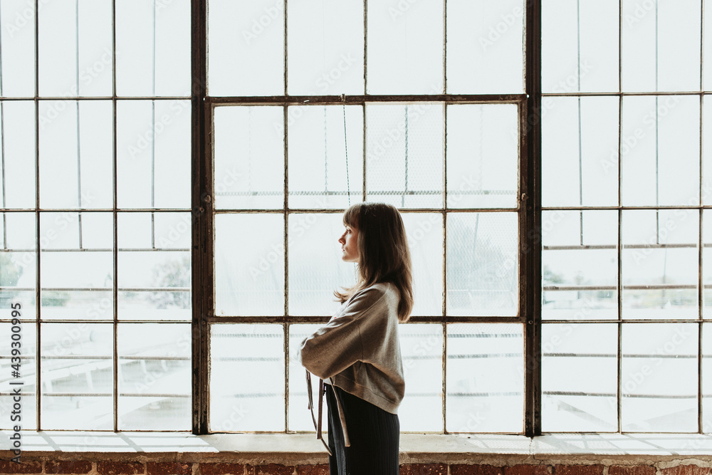 Brown hair woman standing by a window