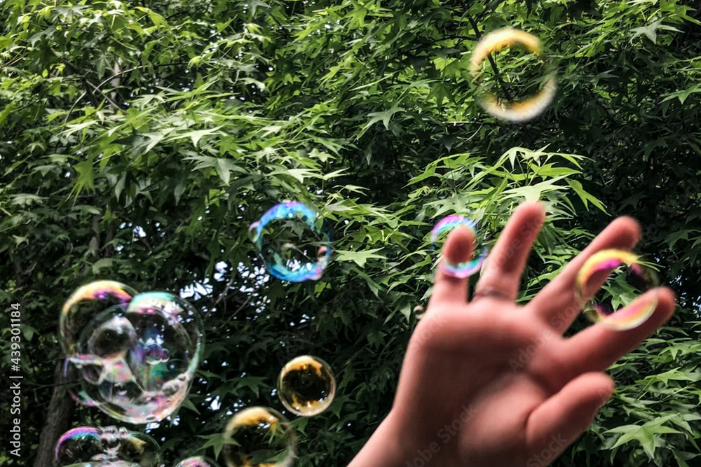 Soap bubbles in the park with kid’s hand closeup