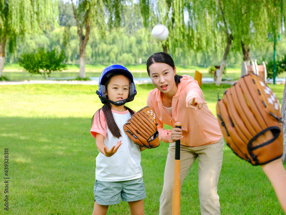 Happy family of three playing baseball in the park