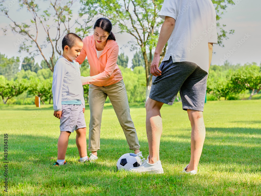 Happy family of three playing football in the park