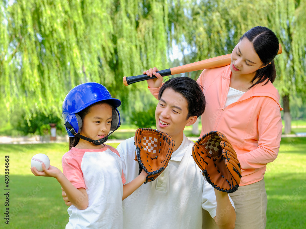 Happy family of three playing baseball in the park