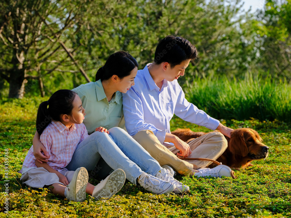 Happy family of three and pet dog playing in the park