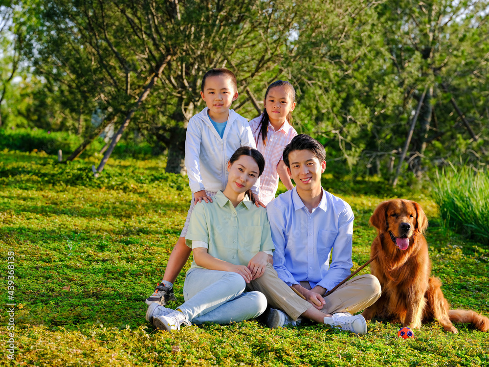 Happy family of four and pet dog in the park