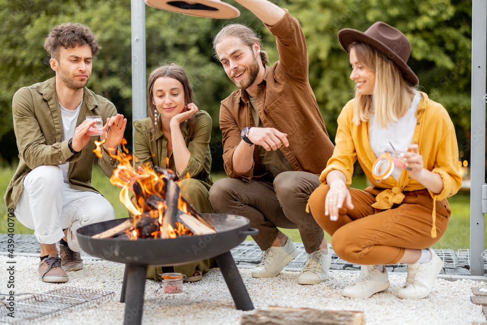 Group of young friends hang out by a fireplace, preparing for grilling at the backyard. Barbecue in 